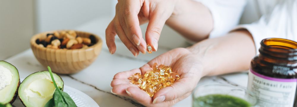 Woman holding vitamin D pills in cupped hand on kitchen counter 