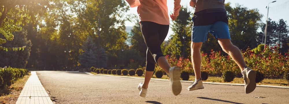 Man and woman jogging together on blacktop outdoor trail 